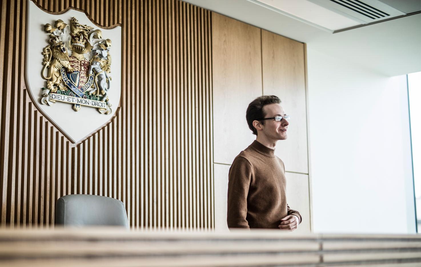 A student in The Oastler Building's Law Courtroom with The Royal Coat of Arms on the wall