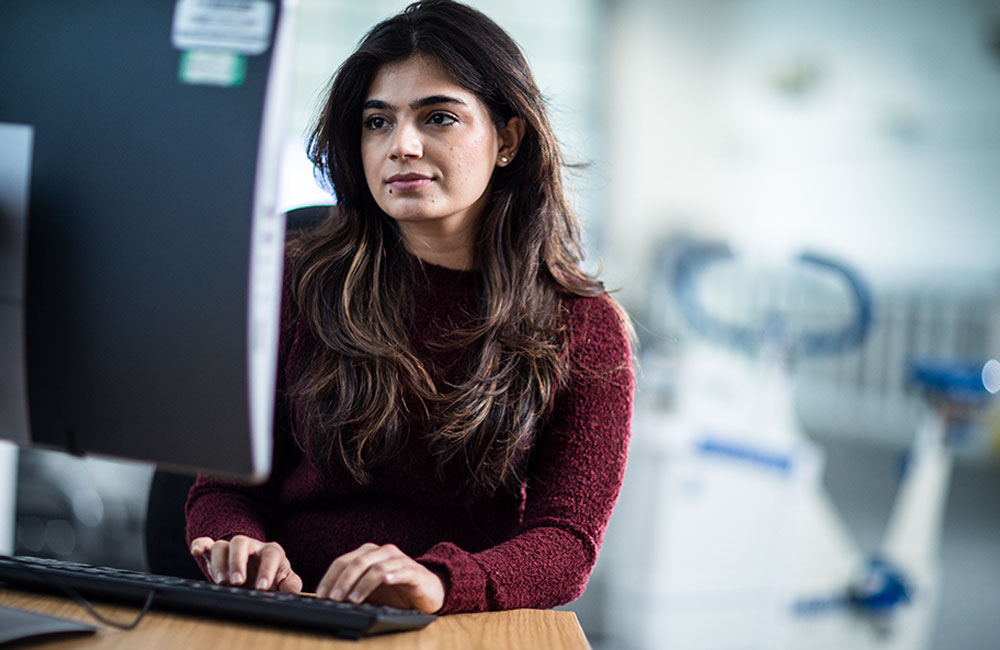 A student sat a desk, working on a computer.