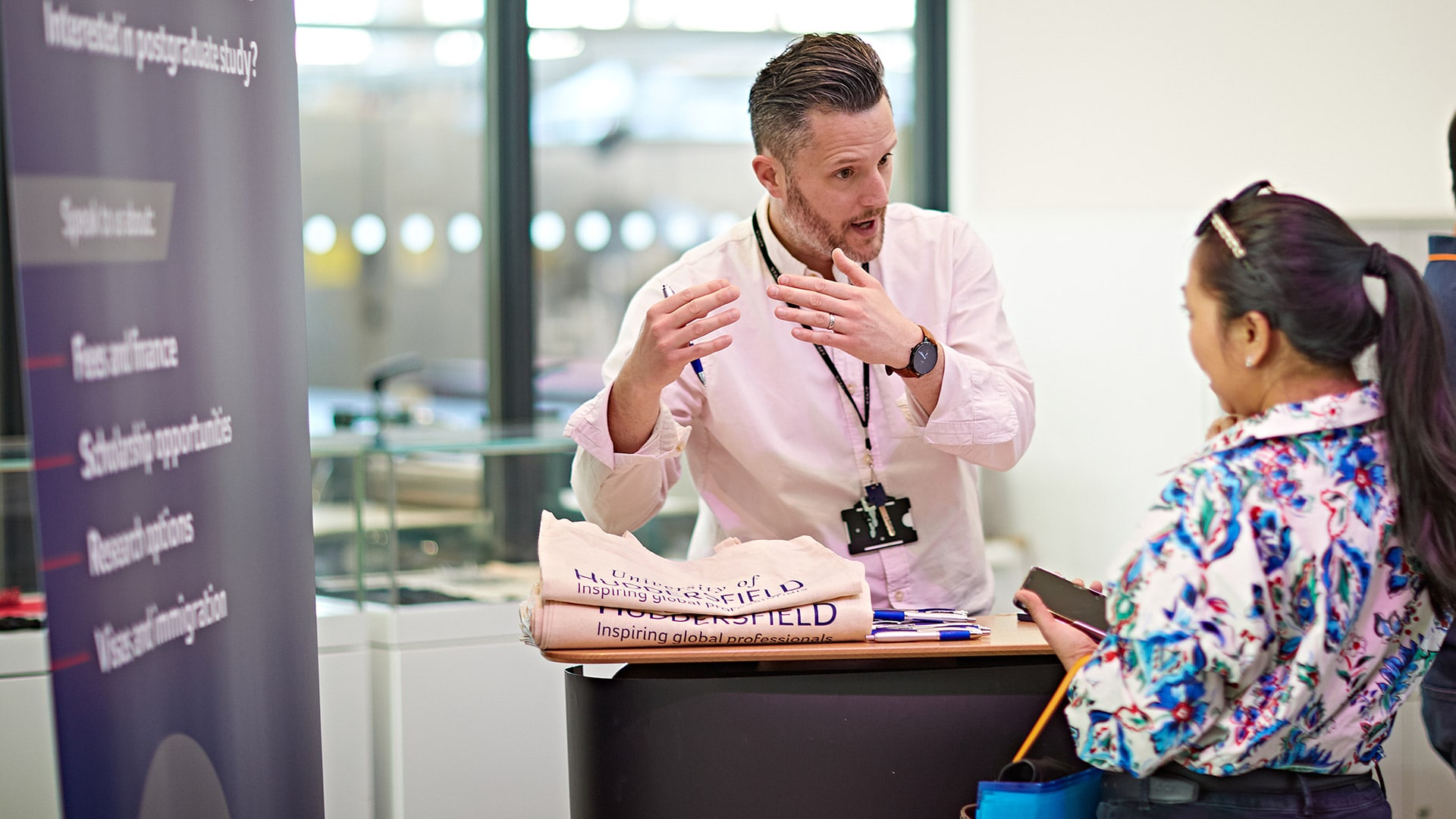 A member of staff talking to a guest at a Postgraduate Open Day.