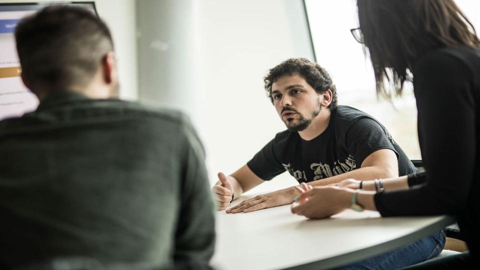 Students sitting at a table, talking to each other.