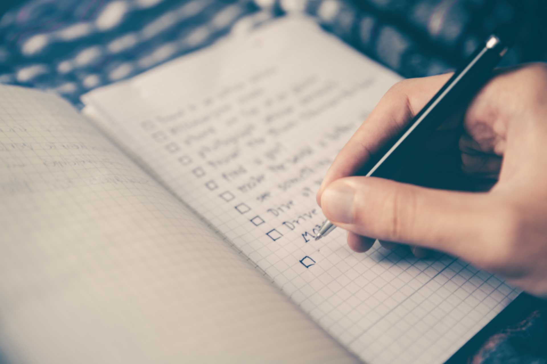 Someone writing a checklist in a notebook
